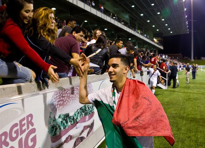 Soccer player wrapped in a Mexican flag shakes hands with spectators Soccer player wrapped in a Mexican flag shakes hands with spectators